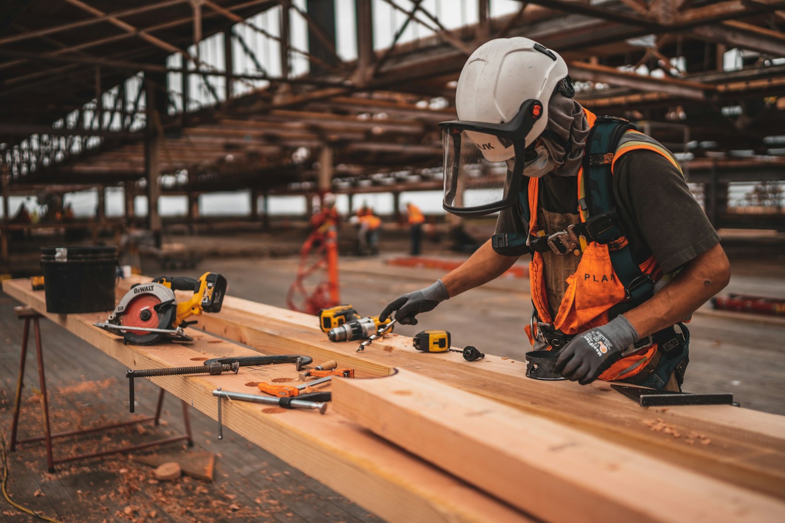 Carpenter in safety gear cutting framing lumber with a circular saw on a jobsite