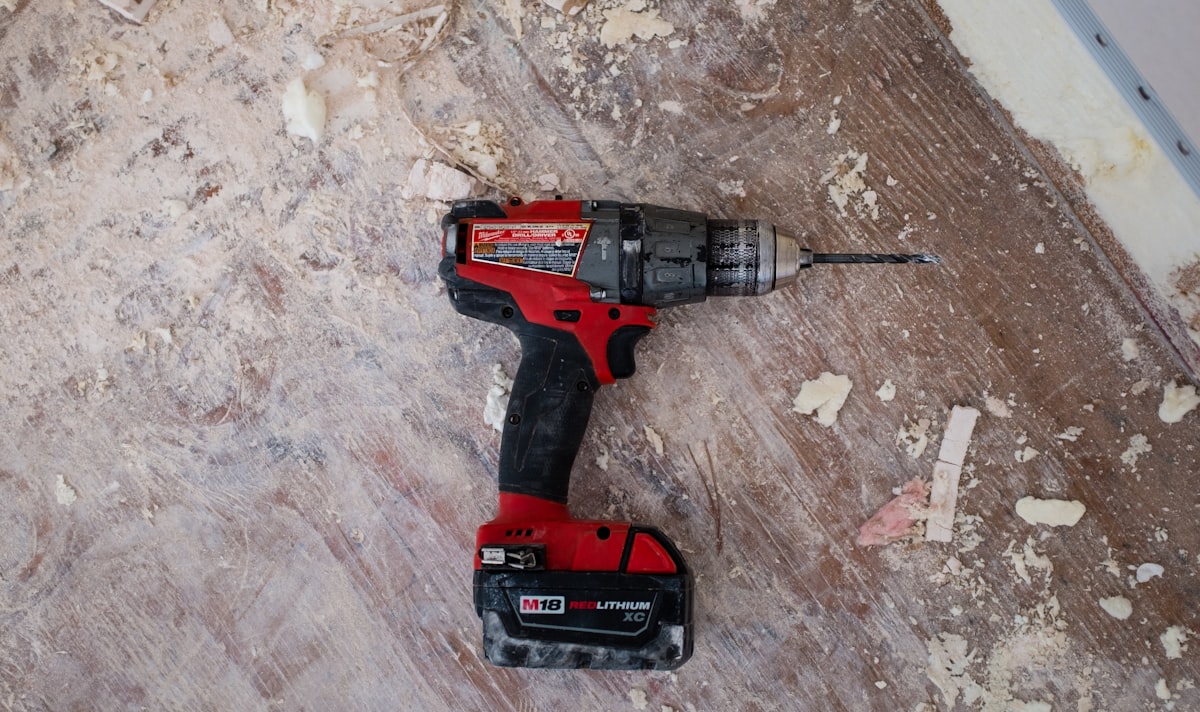 Cordless drill resting on a subfloor mid-repair